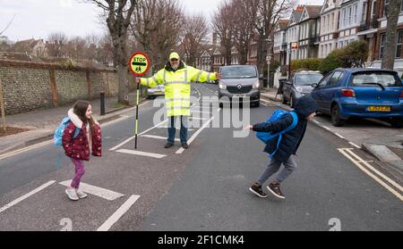 Brighton UK 8 mars 2021 - l'homme Lollipop Simon Moss accueille les enfants de retour à l'école primaire St Luke à Brighton ce matin, car les restrictions de verrouillage du gouvernement en Angleterre commencent à être assouplies . Les écoles et les collèges sont rouverts à tous les étudiants aujourd'hui dans toute l'Angleterre : crédit Simon Dack / Alamy Live News Banque D'Images