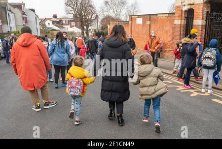 Brighton UK 8 mars 2021 - des enfants et des parents heureux arrivent à l'école primaire St Luke à Brighton ce matin, car les restrictions de verrouillage du gouvernement en Angleterre commencent à être assouplies . Les écoles et les collèges sont rouverts à tous les étudiants aujourd'hui dans toute l'Angleterre : crédit Simon Dack / Alamy Live News Banque D'Images