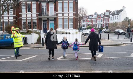 Brighton UK 8 mars 2021 - l'homme Lollipop Simon Moss accueille les enfants de retour à l'école primaire St Luke à Brighton ce matin, car les restrictions de verrouillage du gouvernement en Angleterre commencent à être assouplies . Les écoles et les collèges sont rouverts à tous les étudiants aujourd'hui dans toute l'Angleterre : crédit Simon Dack / Alamy Live News Banque D'Images