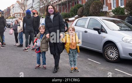 Brighton UK 8 mars 2021 - des enfants et des parents heureux arrivent à l'école primaire St Luke à Brighton ce matin, car les restrictions de verrouillage du gouvernement en Angleterre commencent à être assouplies . Les écoles et les collèges sont rouverts à tous les étudiants aujourd'hui dans toute l'Angleterre : crédit Simon Dack / Alamy Live News Banque D'Images