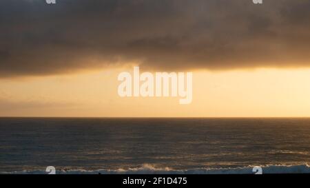 Moody Sunrise tourné avec un océan calme et une couche épaisse de nuages dans le tiers supérieur, tourné à Kaikoura, Nouvelle-Zélande Banque D'Images