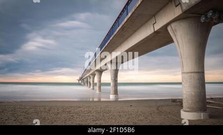 Énorme jetée en béton menant à l'horizon entouré par l'océan. Photo en exposition prolongée réalisée à New Brighton Beach à Christchurch, en Nouvelle-Zélande Banque D'Images