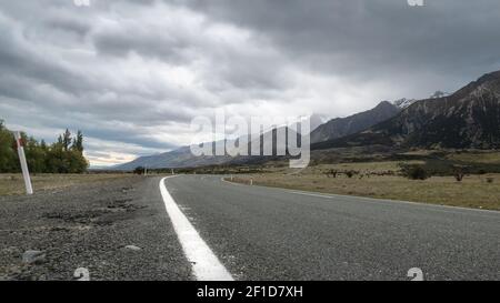 Route menant vers les montagnes, avec ciel nuageux. Photo en perspective basse réalisée dans le parc national d'Aoraki Mt Cook, en Nouvelle-Zélande Banque D'Images