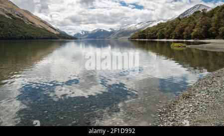 Lac aux eaux cristallines entouré de forêts et de montagnes, tourné aux lacs Mavora, en Nouvelle-Zélande Banque D'Images