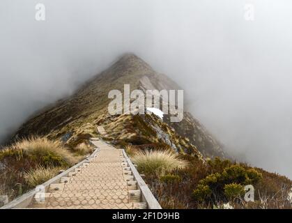 Sentier en bois menant à travers la ridgeline de montagne entourée de brouillard, tourné à Kepler Track, parc national Fiordland, Nouvelle-Zélande Banque D'Images