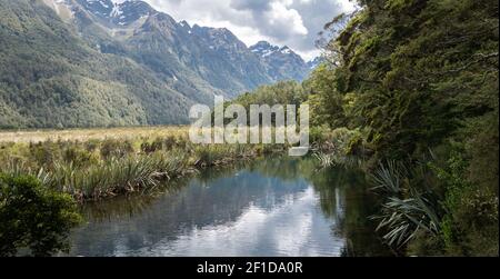 Petite vue sur le lac encadrée par des arbres sur la droite et des montagnes sur la gauche. Photo prise à Mirror Lakes dans le parc national de Fiordland, Nouvelle-Zélande Banque D'Images