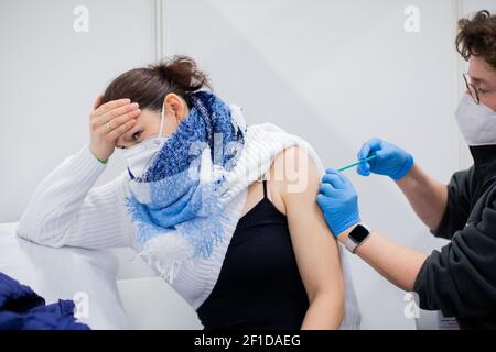 Cologne, Allemagne. 08 mars 2021. Bianca Ahlemeier (32 ans), une garderie de cinq enfants à domicile, est vaccinée avec le vaccin d'AstraZeneca par un médecin du centre de vaccination de Koelnmesse. À partir de 08.03.2021, les enseignants des écoles maternelles, les mineurs, certains enseignants et officiers de police, ainsi que les personnes dans des ateliers pour personnes handicapées, seront vaccinés avec la préparation d'AstraZeneca. Credit: Rolf Vennenbernd/dpa/Alay Live News Banque D'Images