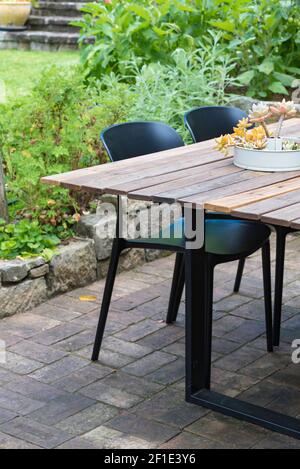 Un cadre de restauration extérieur composé d'une table en bois recyclé et de chaises résistantes aux UV dans une cour pavée en briques à Sydney, en Australie Banque D'Images