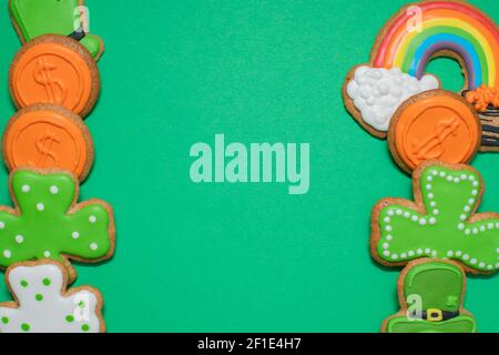 Vue de dessus de la St Patricks fraîchement cuite, biscuits au sucre décorés sur fond vert. Biscuits faits maison avec shamrock, arc-en-ciel, leprechaun et pot de Banque D'Images