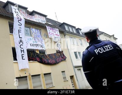 Essen, Allemagne. 08 mars 2021. Un policier observe un immeuble d'appartements occupé par des manifestants à l'arrière de l'ancien siège vacant de la société Hochtief, basée à Essen. Les squatters ont accroché des bannières dans les fenêtres qui lisaient, entre autres choses, « des chambres pour tous ceux qui en ont besoin - le squattage n'est pas un crime » (ci-dessous). Crédit : Roland Weihrauch/dpa/Alay Live News Banque D'Images