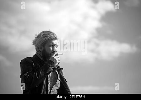 Cool homme méditerranéen avec la barbe fumer à l'extérieur dans l'environnement urbain Banque D'Images