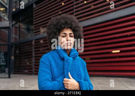 Photo de la femme afro expressive portant un manteau bleu froid regardant l'appareil photo. Banque D'Images