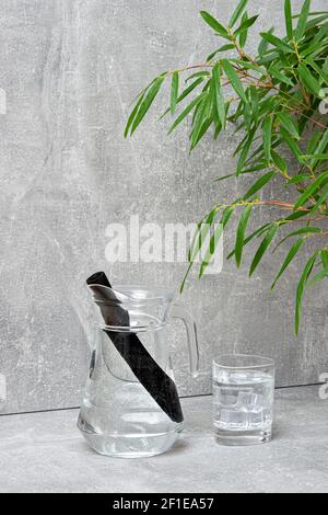 Bâton de filtre à eau en bambou, feuille verte et verre d'eau. Le charbon de bambou naturel est un purificateur puissant qui rafraîchit l'eau du robinet Banque D'Images