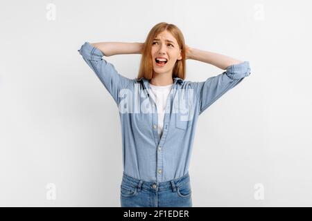 Portrait d'une femme agressive triste insatisfaite couvrant les oreilles avec les paumes sur fond blanc Banque D'Images