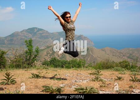 Feodosia, CRIMÉE-Mai 2018:une fille sourit, une fille sportive dans un saut, les mains soulevées Banque D'Images