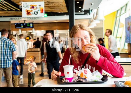 Berlin, Allemagne. Jeune adulte, étudiant en musique de sexe masculin mangeant un ensemble malsain de hamburgers au restaurant McDonald's fastfood pendant son déjeuner. Banque D'Images