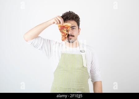 Image d'un cuisinier de sexe masculin montrant une tranche de pizza sur du blanc arrière-plan Banque D'Images