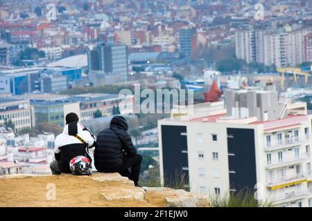 Vue arrière de deux amis dans une colline assis ensemble tout en regardant le paysage urbain. Banque D'Images