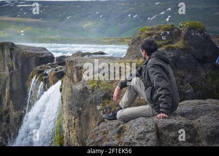 Jeune homme sur le bord de la cascade Godafoss en Islande. Banque D'Images