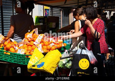 PARIS, FRANCE - 1er SEPTEMBRE 2018 : femme choisissant des oranges au marché de rue Beauvau. Banque D'Images