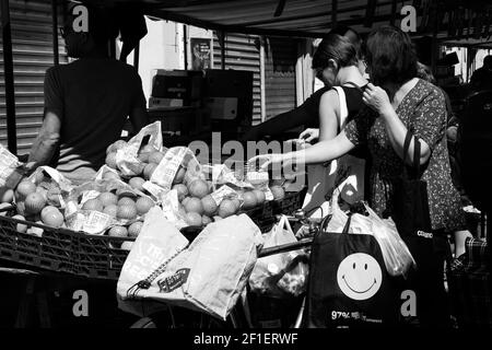 PARIS, FRANCE - 1er SEPTEMBRE 2018 : femme choisissant des oranges au marché de rue Beauvau. Photo en noir et blanc. Banque D'Images