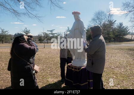 À la fin d'un service de plein air, les fidèles de l'Apostolat mondial de Saint Michel prient à une statue de la Vierge Marie. Dans un parc à New York. Banque D'Images