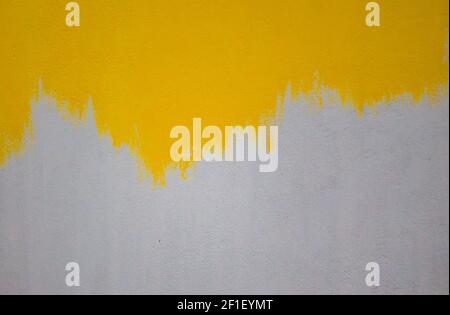 mur en béton peint en jaune vif. peinture appliquée sur apprêt blanc. arrière-plan abstrait de l'espace de copie avec motif. photo extérieure. Banque D'Images