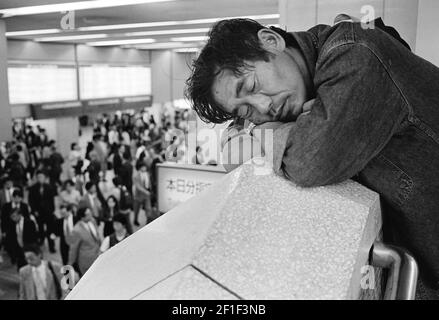 Les personnes qui marchent à pied après un homme sans abri dormant dans le métro, Tokyo, Japon Banque D'Images