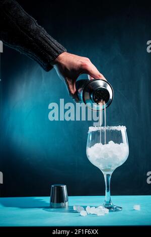 Main d'un barman ajoutant du sirop à un cocktail avec de la glace Banque D'Images