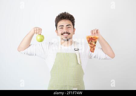 Portrait d'un cuisinier souriant montrant de la pizza et de la pomme verte sur fond blanc Banque D'Images