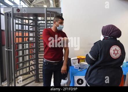 Lamed Hei Checkpoint, Palestine, 8 mars 2021. Un medic de l'agence israélienne d'urgence Magen David Adam inocule un travailleur palestinien avec la première dose du vaccin Moderna COVID-19 au point de contrôle de Lamed Hei entre Gush Etzion et Beit Shemesh, le lundi 8 mars 2021. Israël a lancé une campagne de deux semaines pour vacciner quelque 100,000 travailleurs palestiniens de Cisjordanie qui détiennent des permis de travail en Israël et dans les colonies juives. Crédit : UPI/Alay Live News Banque D'Images