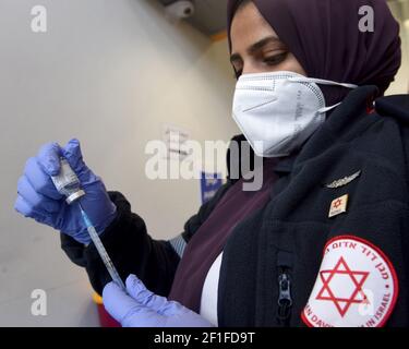 Lamed Hei Checkpoint, Palestine, 8 mars 2021. Un medic de l'agence israélienne d'urgence Magen David Adam se prépare à inoculer à un travailleur palestinien la première dose du vaccin Moderna COVID-19 au point de contrôle de Lamed Hei entre Gush Etzion et Beit Shemesh, le lundi 8 mars 2021. Israël a lancé une campagne de deux semaines pour vacciner quelque 100,000 travailleurs palestiniens de Cisjordanie qui détiennent des permis de travail en Israël et dans les colonies juives. La campagne de vaccination est un projet conjoint du Ministère israélien de la santé, du Ministère de la défense, de l'Autorité de passage des terres et de la coordination de Govern Banque D'Images