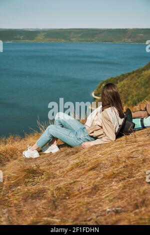 Femme aux cheveux foncés vêtue de vêtements décontractés sur une colline verdoyante pendant la randonnée dans la région de Bakota. Bonne femme passant du temps libre dans le parc national ukrainien. Banque D'Images