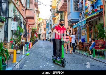 La vie ordinaire dans le vieux quartier d'Istanbul. Deux gars sont à cheval le long d'une rue étroite sur un scooter électrique. Turquie , Istanbul - 21.07.2020 Banque D'Images