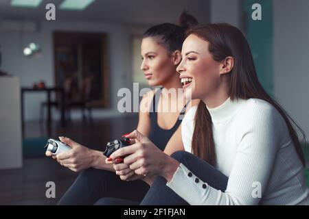 De jeunes amis caucasiens heureux jouant sur la console à la maison, en riant tout en appréciant le jeu vidéo Banque D'Images
