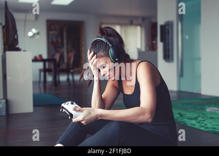 La jeune femme triste échoue pendant le jeu de console à la maison Banque D'Images