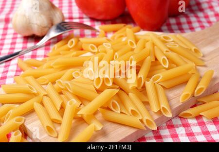 Rigate de penne brute vu d'en haut. Pâtes italiennes sèches sur planche à découper en bois. Cuisine italienne. Banque D'Images