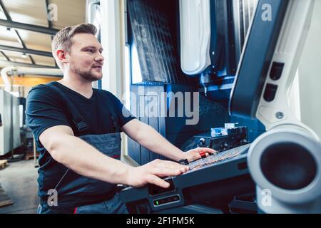 Machine-opérateur programmant un tour CNC industriel moderne Banque D'Images