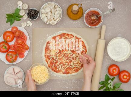 Préparation étape par étape de pizza maison avec jambon, étape 5 - ajouter le fromage râpé à la sauce Banque D'Images