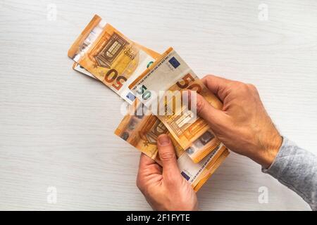 Homme remet en main le comptage des billets de banque en euros et la calculatrice table blanche Banque D'Images