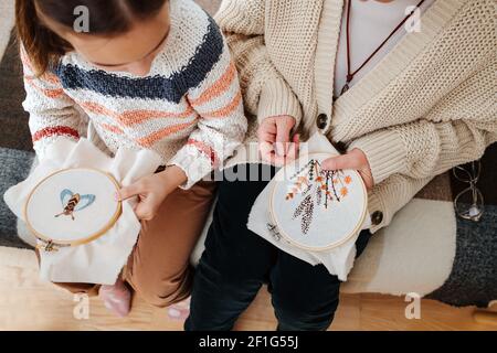 Gros plan des mains de l'enfant et de la femme âgée, ils conservent leur broderie dans les cerceaux. Banque D'Images