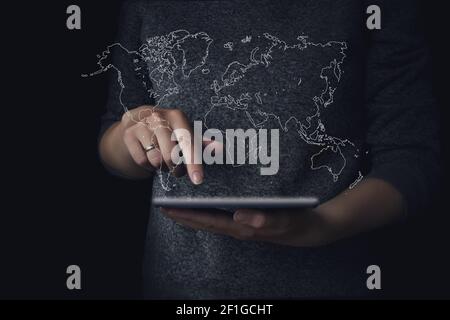 Femmes adolescentes utilisant une tablette avec la carte du monde hologramme Banque D'Images