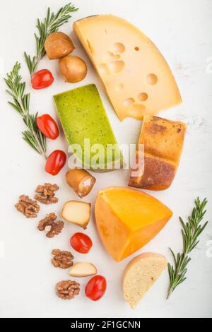 Ensemble de différents types de fromage au romarin et aux tomates sur fond de bois blanc. Vue de dessus, plan d'installation, gros plan. Banque D'Images