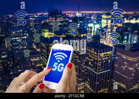 5G ou LTE présentation. Femme la main à l'aide du smartphone Blackberry avec la ville moderne sur l'arrière-plan Banque D'Images
