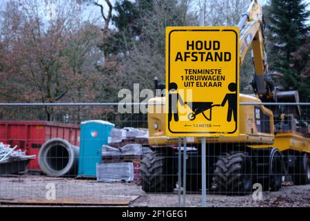 Amersfoort,pays-Bas-JAN,31,2021:signe de distance sociale du virus Corona sur le site de construction. Texte néerlandais : gardez votre distance, au moins 1 brouette Banque D'Images