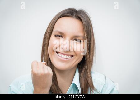 Gros plan de jeune gaie heureux célébrant la femme d'affaires avec le sourire blanc parfait faisant le geste gagnant. Succès commercial Banque D'Images