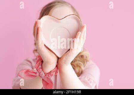 Gros plan sur une fille avec une soucoupe en forme de coeur isolée sur fond rose. Banque D'Images