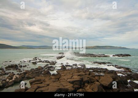 Des vagues sauvages de l'océan Pacifique s'écrasont sur des rochers à l'entrée de la baie de Porpoise, côte rugueuse du sud, Nouvelle-Zélande Banque D'Images