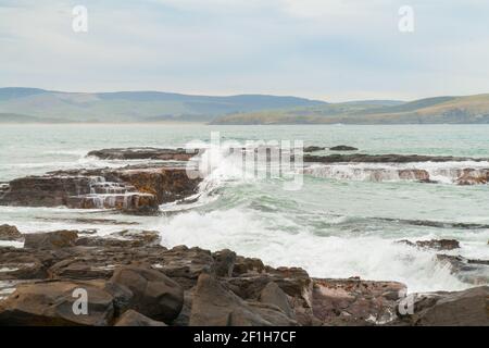 Des vagues sauvages de l'océan Pacifique s'écrasont sur des rochers à l'entrée de la baie de Porpoise, côte rugueuse du sud, Nouvelle-Zélande Banque D'Images