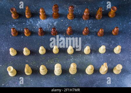 Une vue de dessus des figures d'échecs en bois arrangé au départ positionner sur une surface bleue Banque D'Images